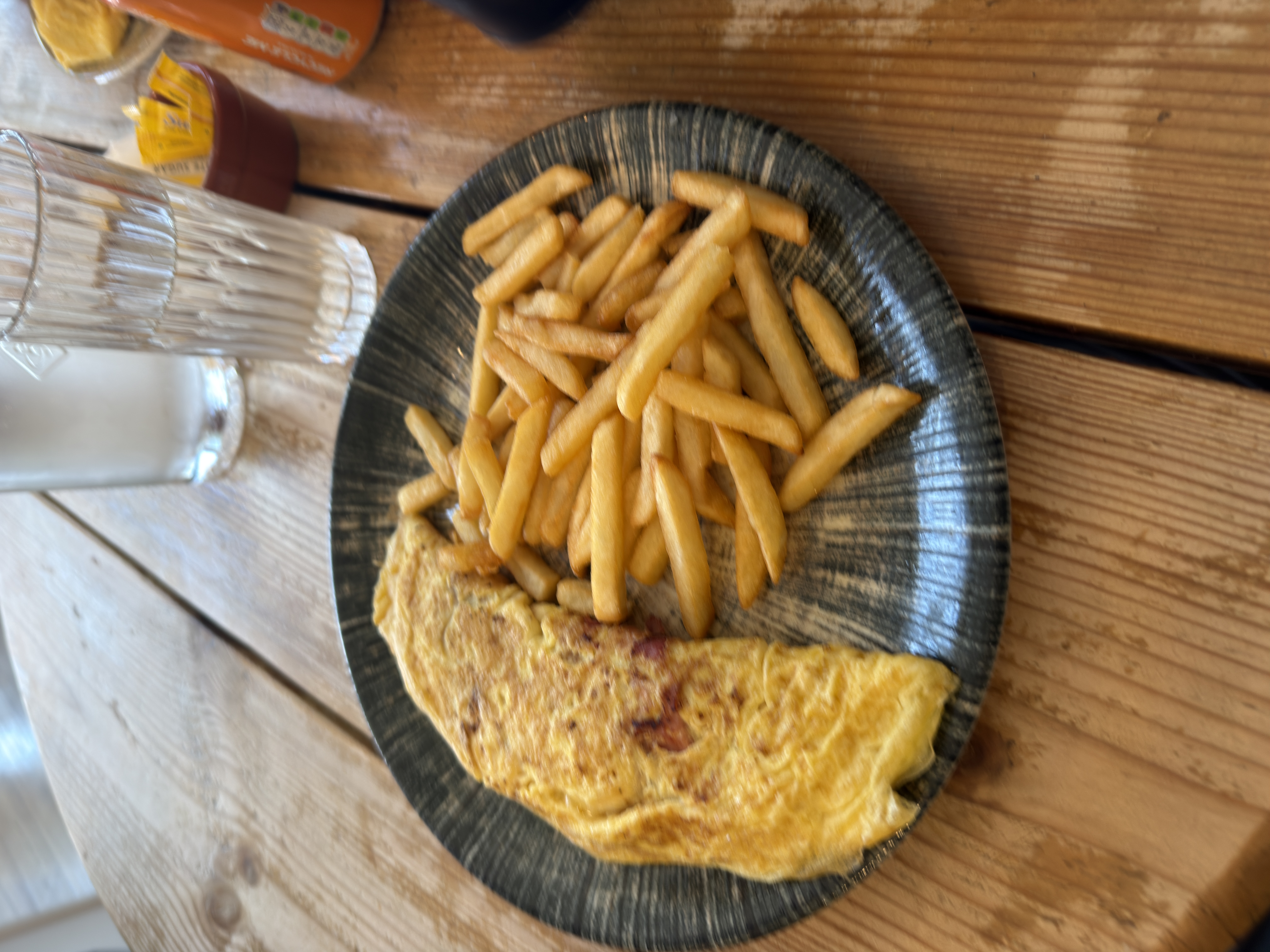 Omelette and chips on a dark stoneware plate at The Aerodrome Café, Elstree EGTR, on a sunny lunchtime.