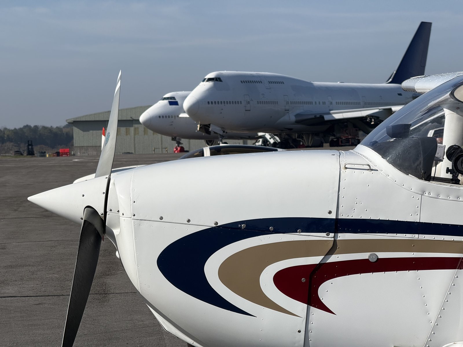 KK nose and prop with two stored 747s behind. Little plane, big jets, whole story in one frame.